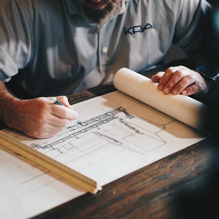 man sketching blueprints