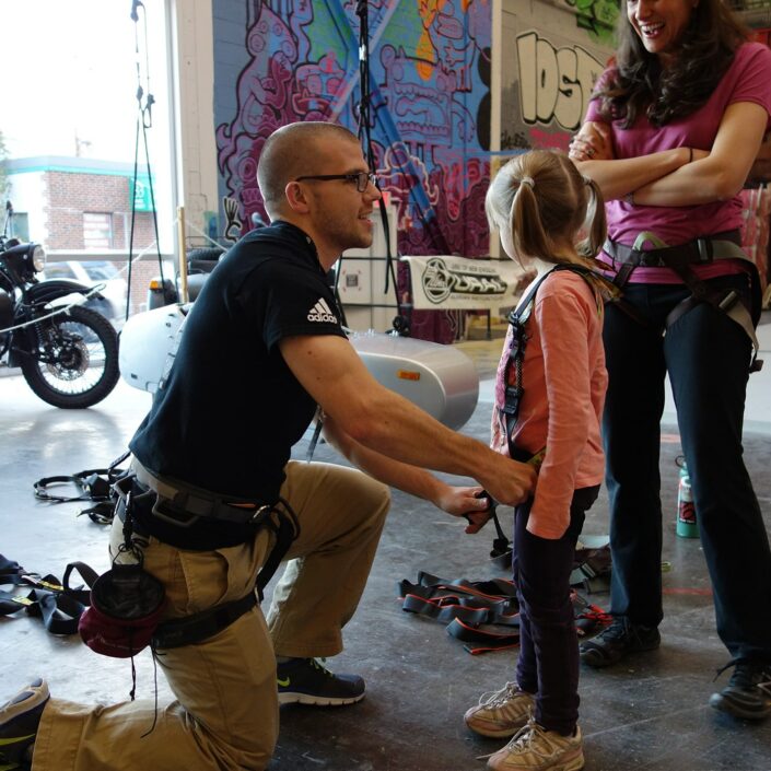 man helping child with climbing harness